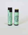 Two green lip balms with black caps on a white background, Peppermint tallow lip balm
