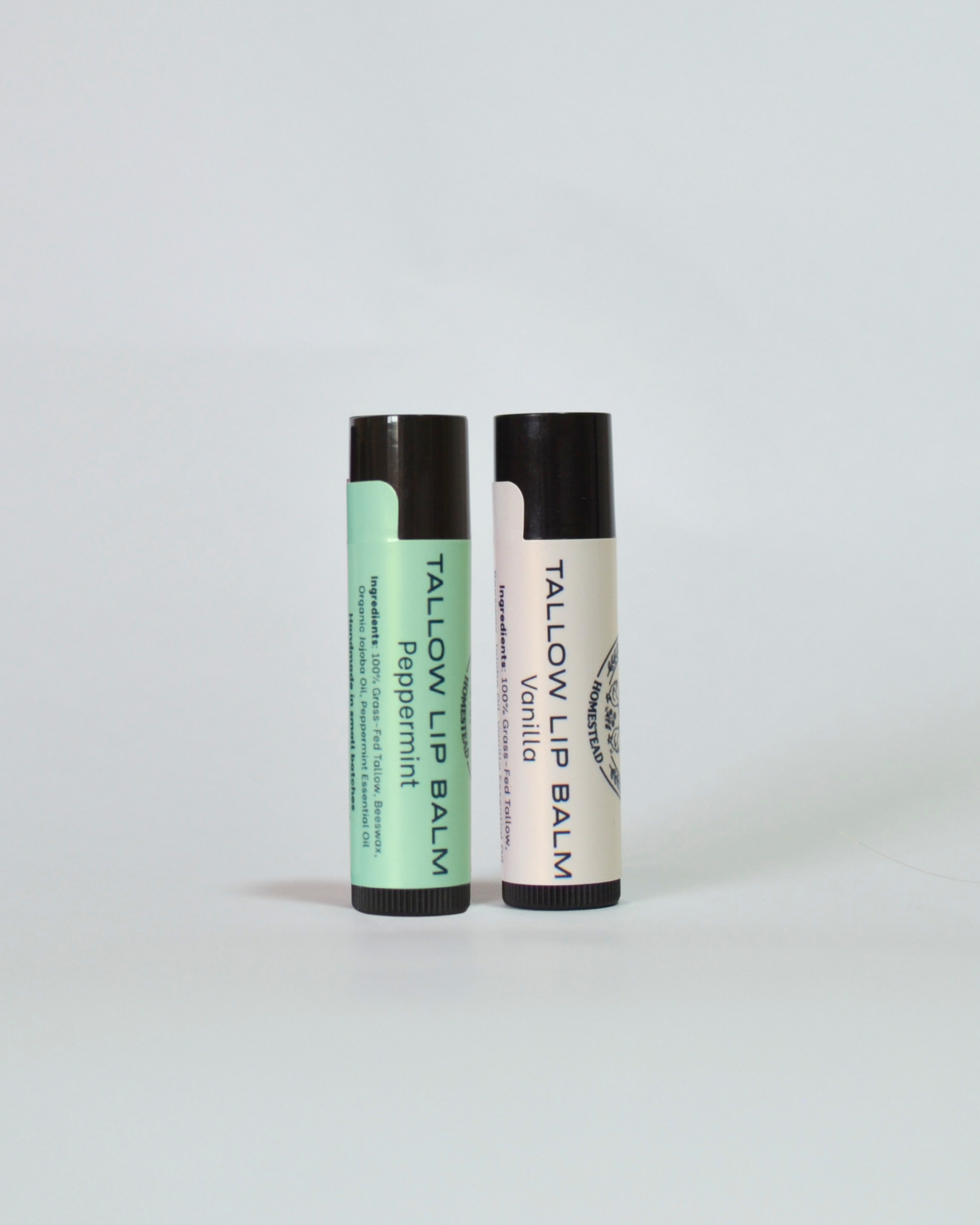 Two lip balm tubes, one green and one white, on a light gray background. Peppermint. Vanilla
